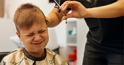 Consejos para un desarrollo saludable con Integración Sensorial Nino recibiendo un corte de pelo malumorado, requiere terapia de integración sensorial para regular su sistema propioceptivo.